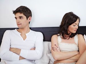 Couple in bed looking annoyed and not speaking to one another